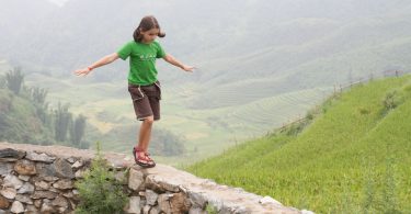 Reiseführer Vietnam Sapa Mädchen auf Mauer vor Reisfeldern